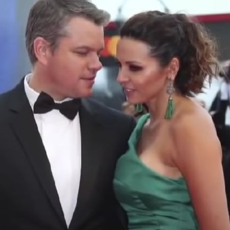 Matt Damon and Luciana Barroso are posing on the red carpet as he is looking at his wife.